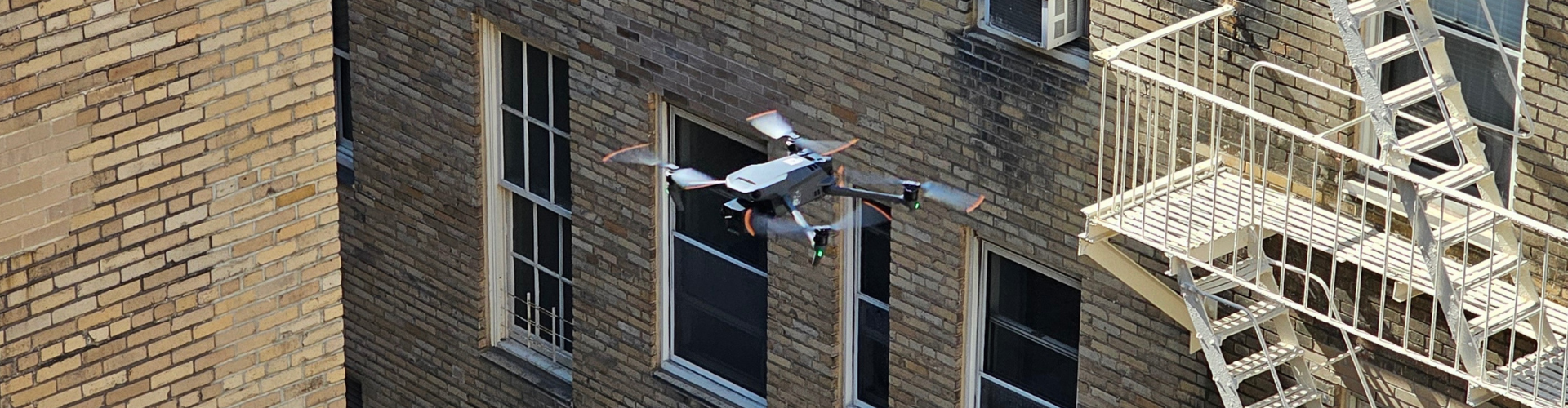 Drone inspecting brick building façade and fire escape in NYC for Local Law 11 compliance